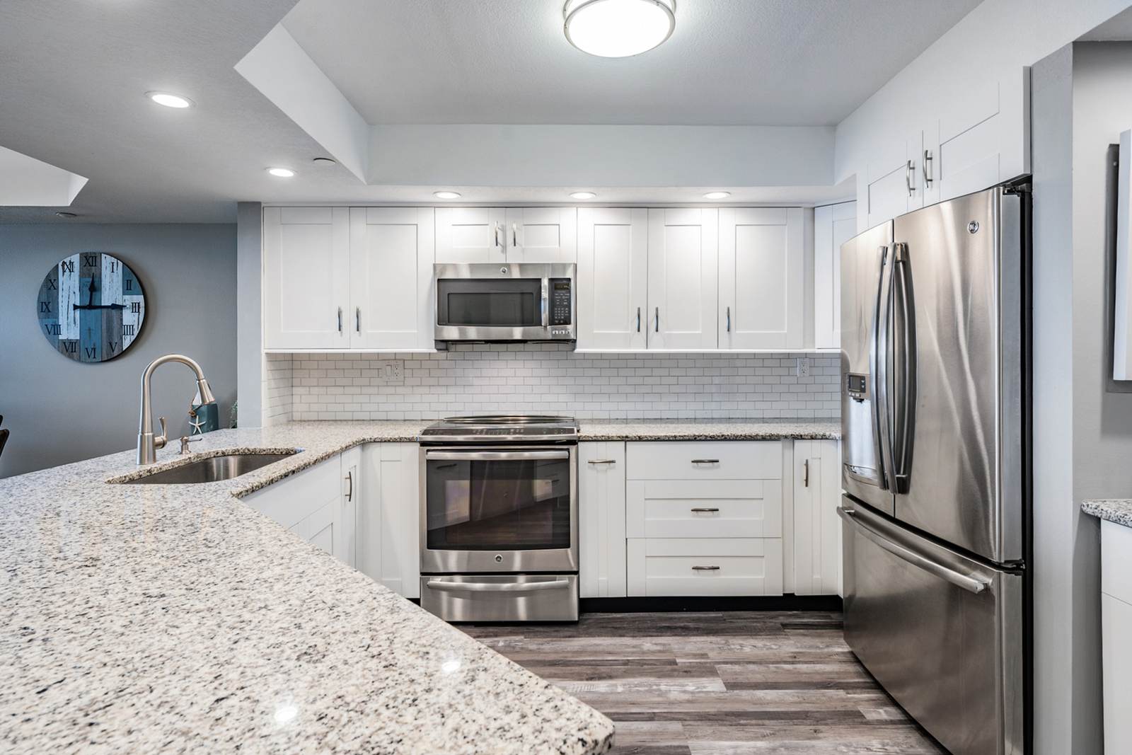 Renovated kitchen with white cabinets, granite counters, and stainless appliances